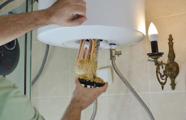 Technician removing mineral buildup from a water heater in Fountain