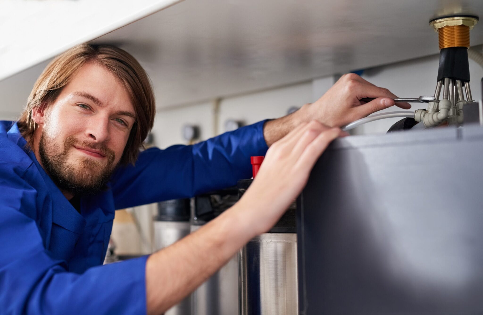 Technician servicing a residential water heater tank in Fountain