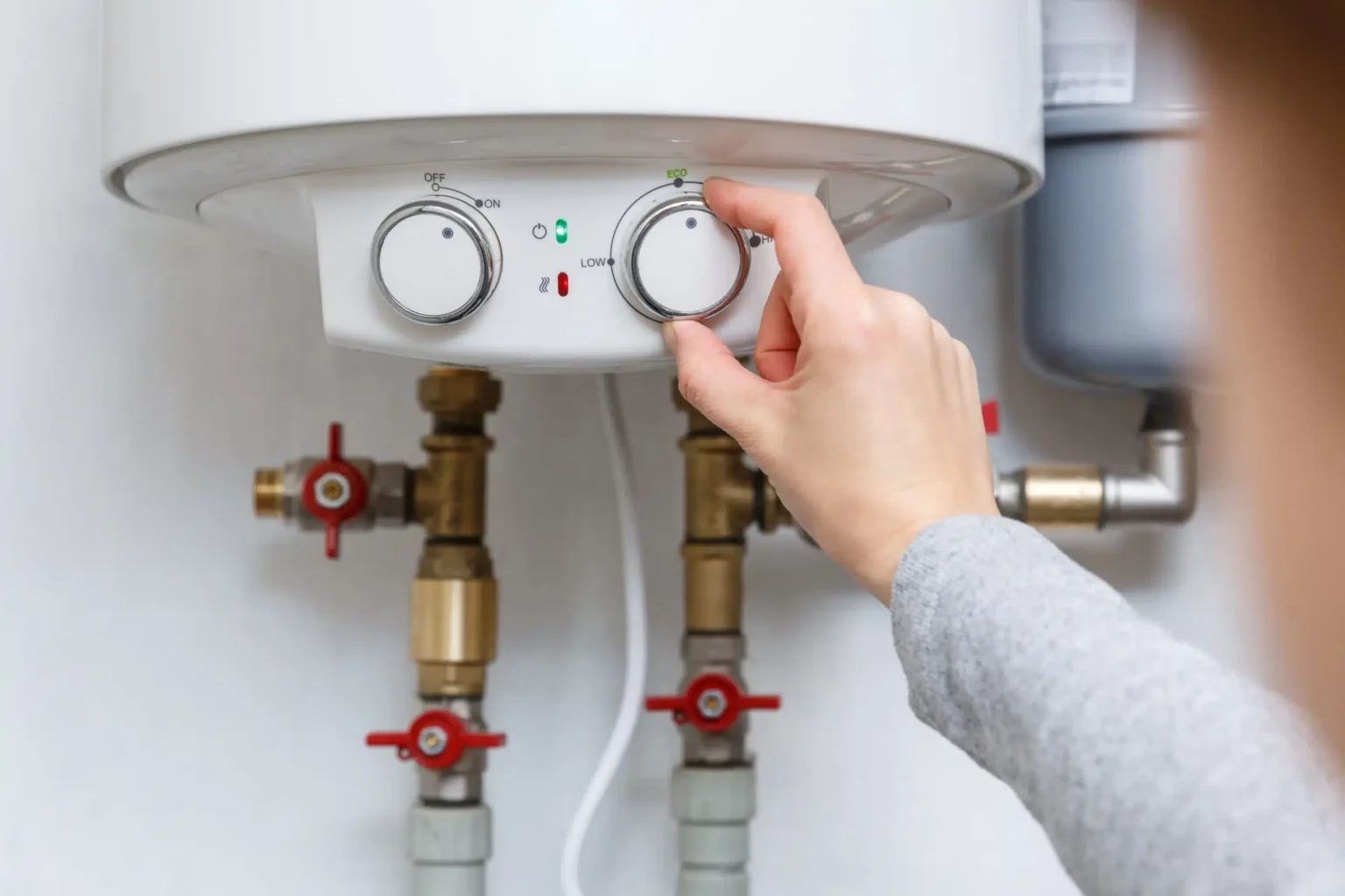 Homeowner adjusting the temperature controls on a water heater in Fountain